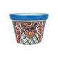 A small hand-painted ceramic pot with a vibrant blue rim and a colorful, intricate floral pattern on a white background.