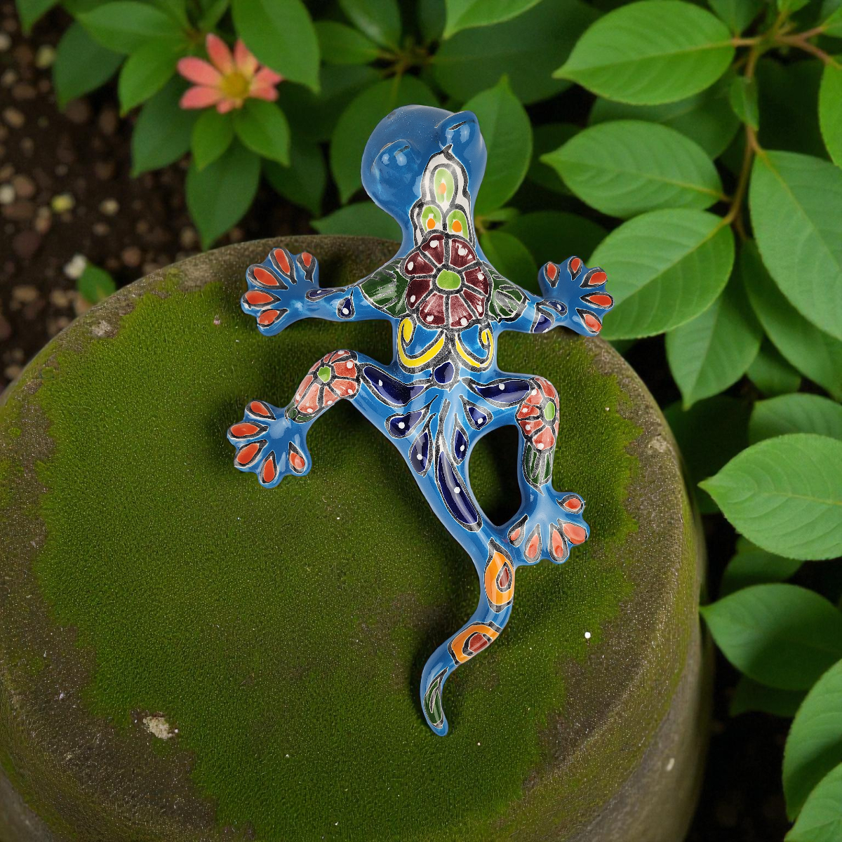 Colorful ceramic salamander on a green surface with leaves in the background