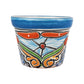 A small hand-painted ceramic planter pot with a vibrant blue rim and a colorful hand-painted floral and scroll pattern in orange, green, white, and black on a white background.