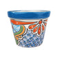 A small hand-painted ceramic planter pot with a blue glazed rim and a colorful hand-painted floral and geometric pattern on a white background.