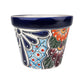 A small hand-painted ceramic planter pot with a dark blue glazed rim and a colorful floral and geometric pattern on a white background.