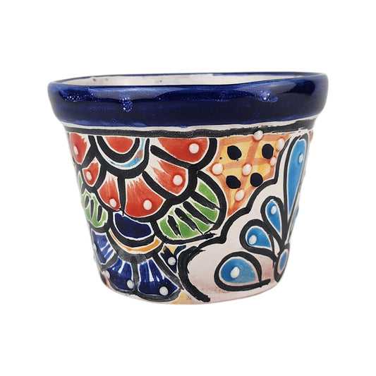 A small hand-painted ceramic planter pot with a vibrant Mexican Talavera style design, featuring a deep blue glazed rim and multicolored floral and geometric patterns on a white base, isolated on a white background.
