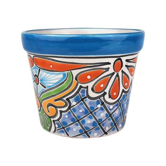 A small hand-painted ceramic planter pot with a vibrant blue rim, blue polka-dot patterned base, and orange, green, and white floral and scroll motifs, shown on a plain white background.