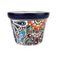 A small hand-painted ceramic pot with a dark blue glazed rim and a colorful floral pattern on a white background.