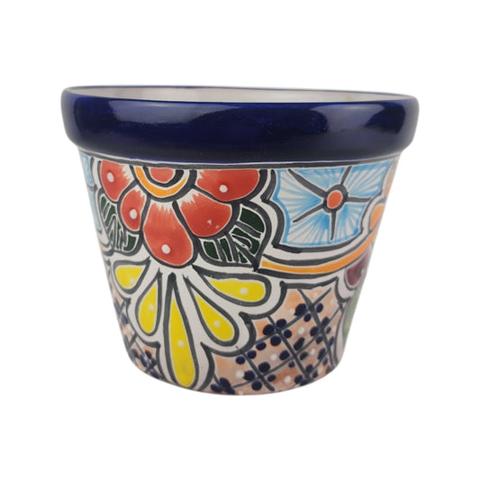 A small hand-painted ceramic planter pot with a dark blue glazed rim and a colorful floral pattern on a white background.