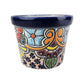 A small hand-painted ceramic pot with a dark blue glazed rim and a colorful floral and scroll pattern on a light beige background.
