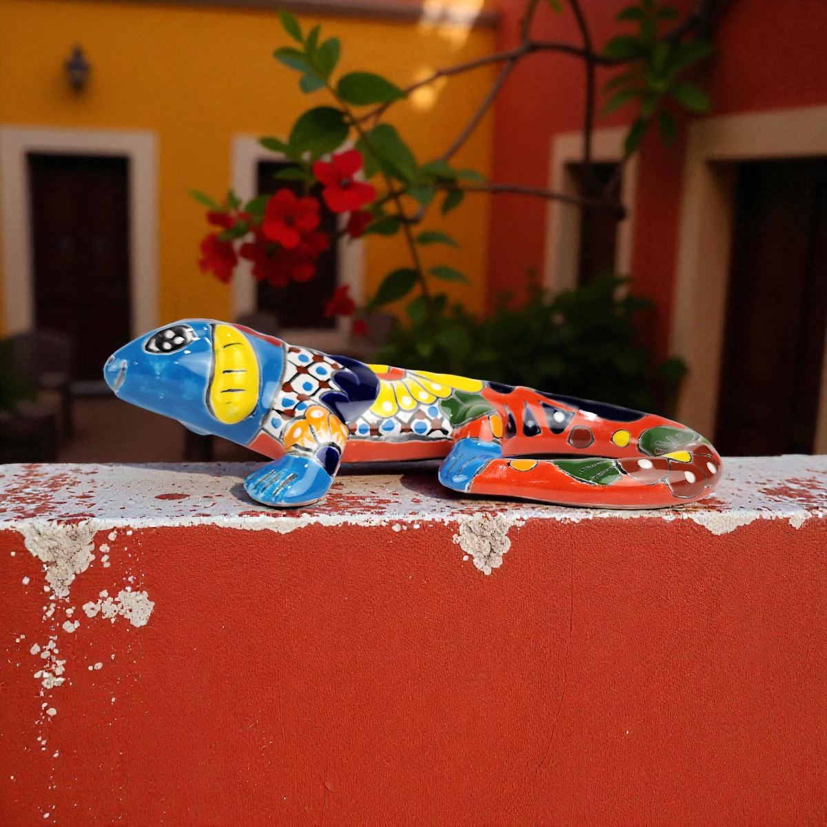 Colorful ceramic iguana sculpture on a red surface with a blurred background