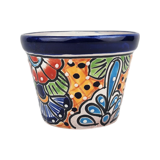 A small hand-painted ceramic planter pot with a vibrant floral pattern in orange, blue, green, red, and black on a white base, featuring a solid dark blue glazed rim.