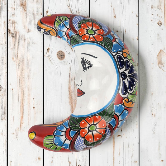 Red Talavera-style ceramic moon wall décor with colorful floral patterns on rustic white wood background