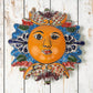 Blue Talavera-style ceramic sun wall décor with colorful floral and geometric patterns on rustic white wood background