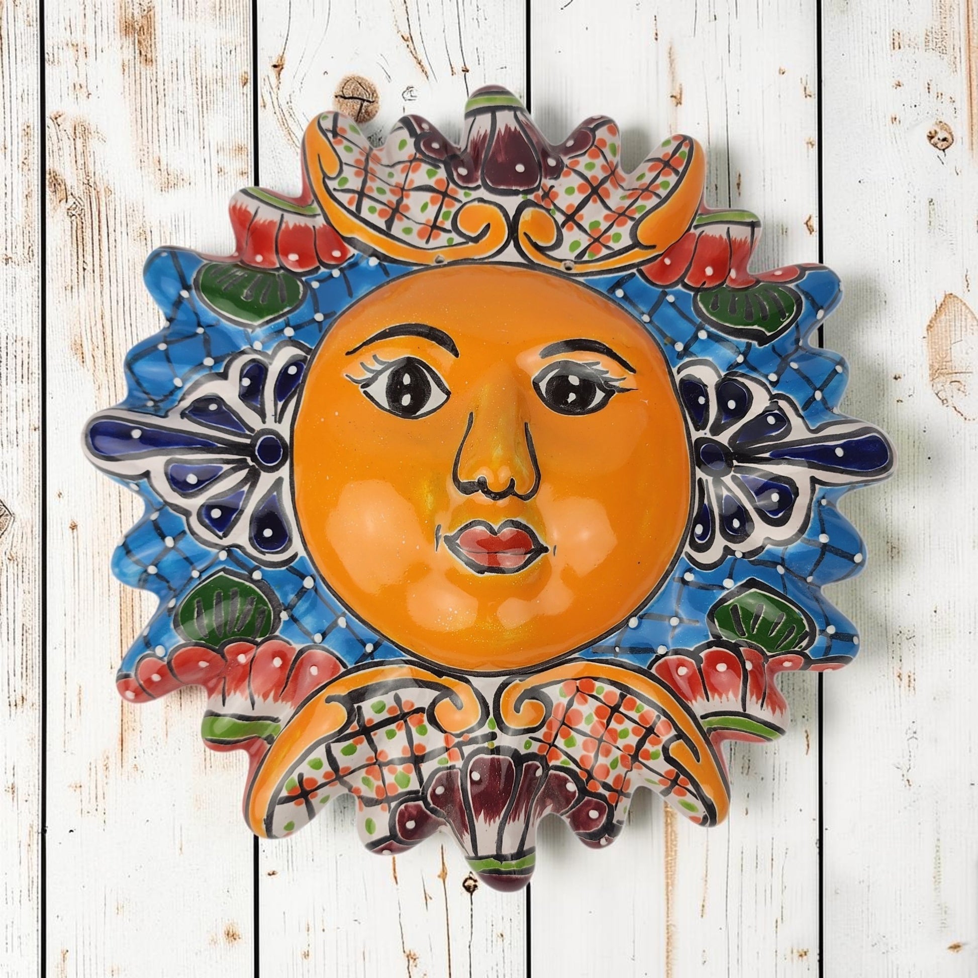 Blue Talavera-style ceramic sun wall décor with colorful floral and geometric patterns on rustic white wood background