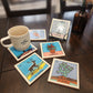 Set of colorful coasters with various designs on a wooden surface, accompanied by a mug.