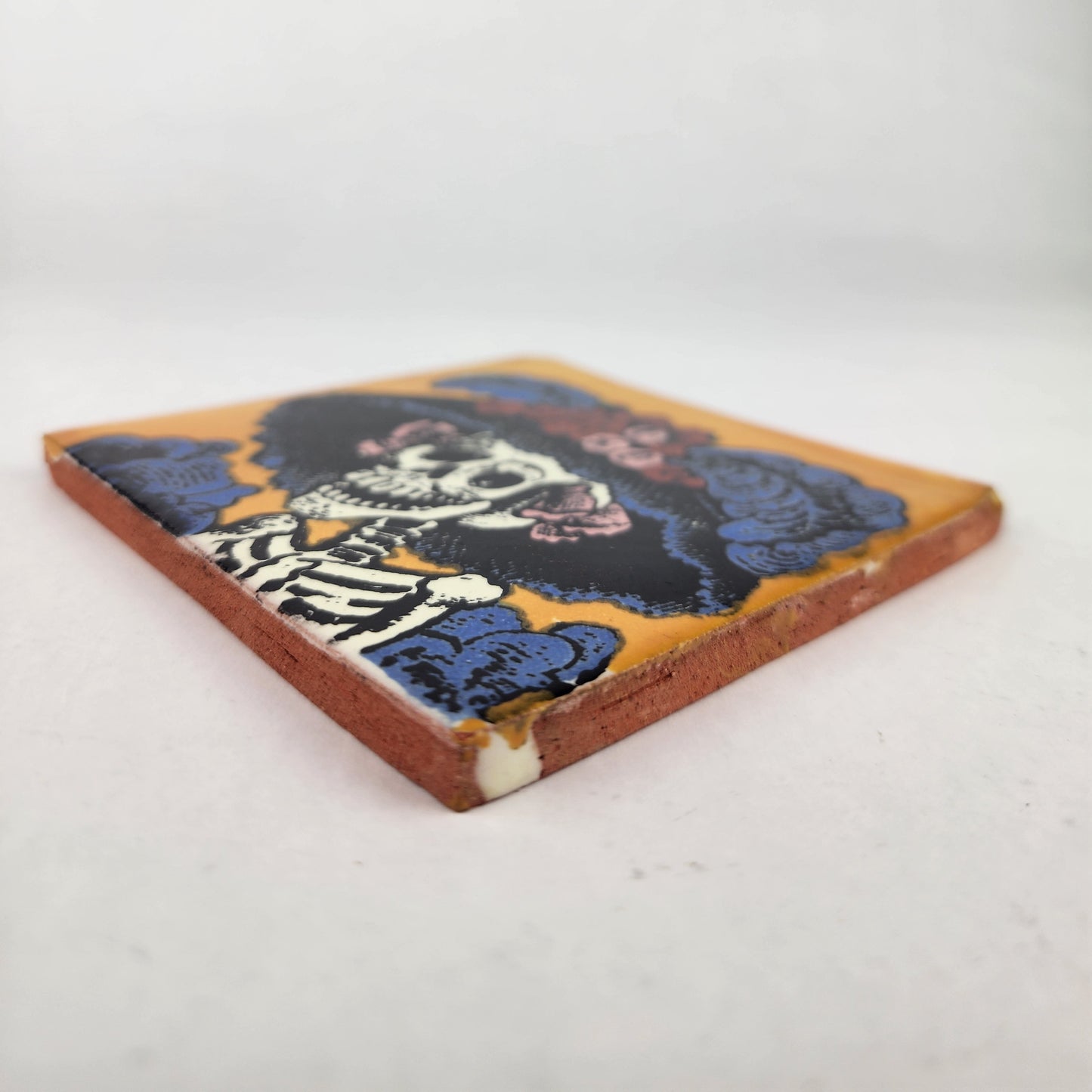 Angled view of golden yellow Catrina Portrait ceramic tile showing glossy surface and natural terracotta edges