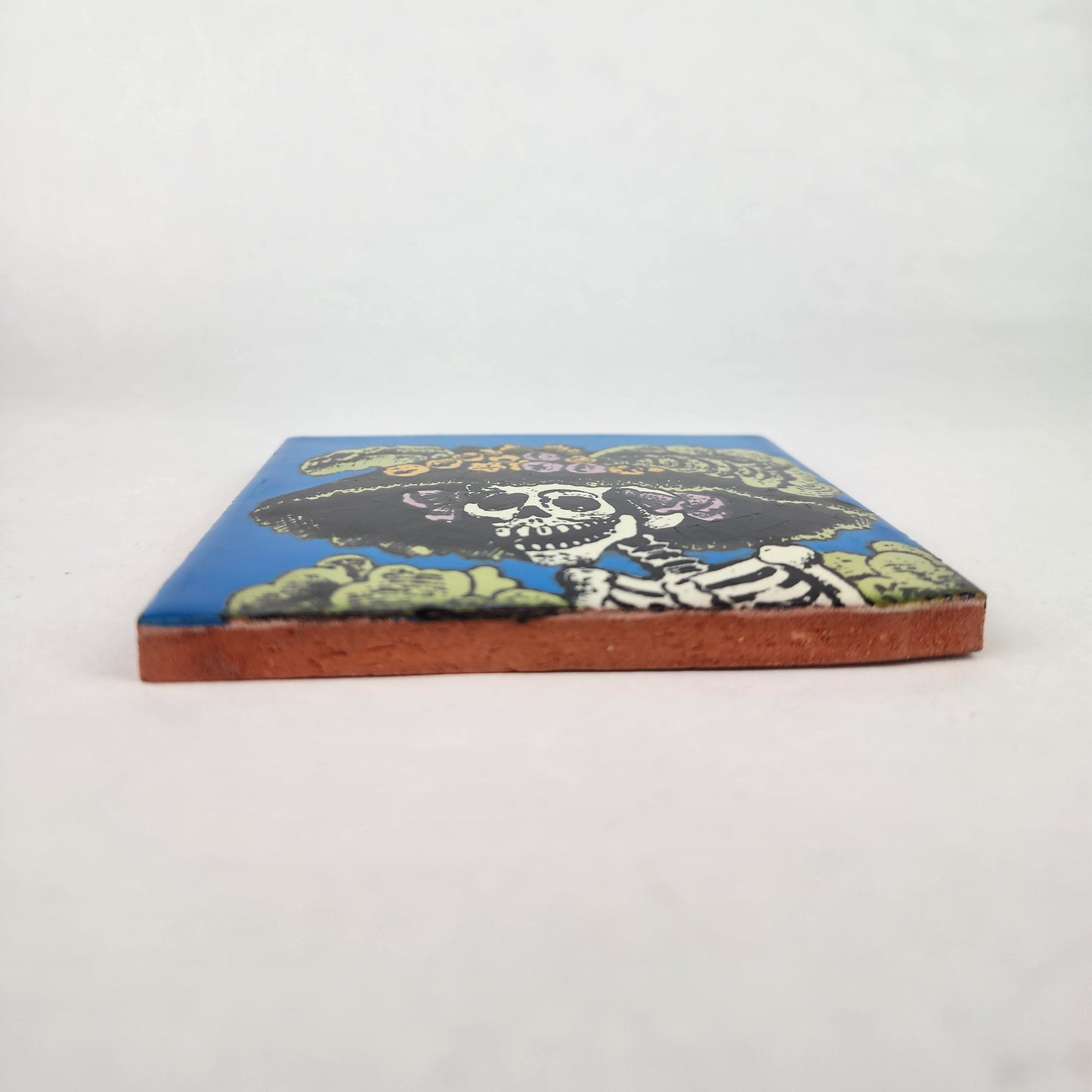 Sky blue Catrina Portrait ceramic tile shown from front edge highlighting ceramic thickness and natural terracotta edge