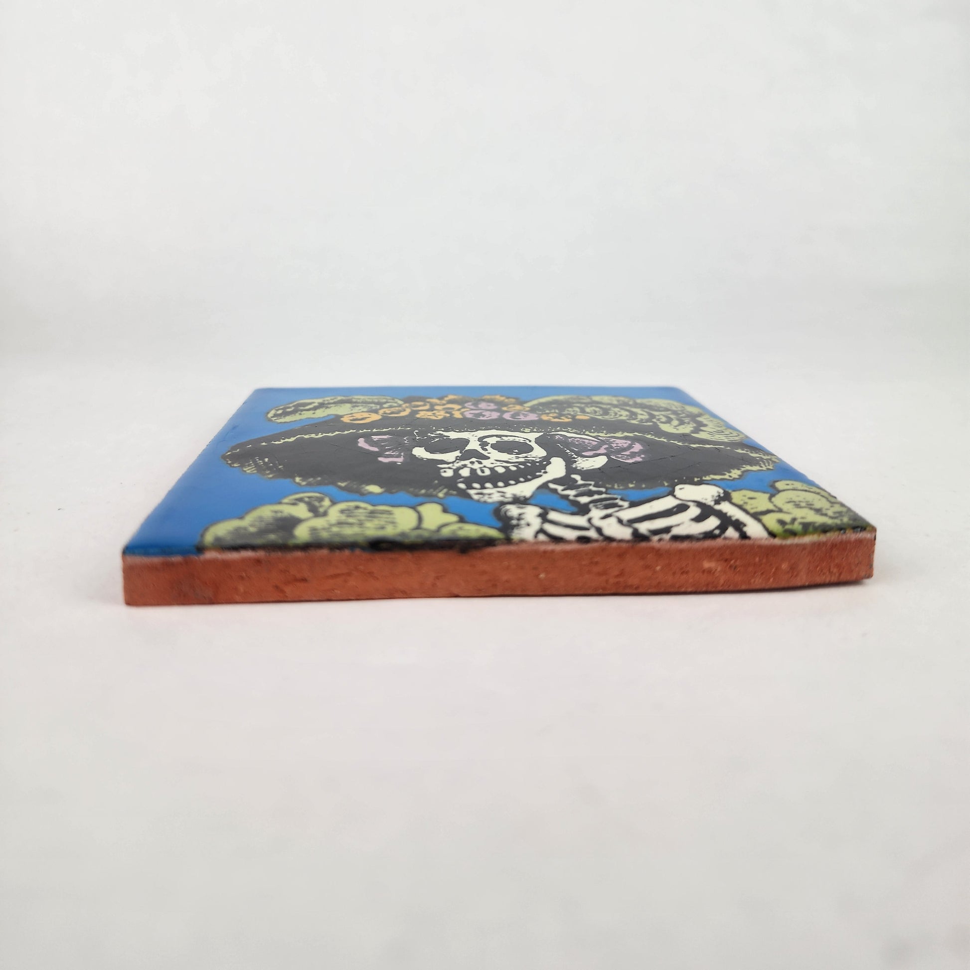 Sky blue Catrina Portrait ceramic tile shown from front edge highlighting ceramic thickness and natural terracotta edge
