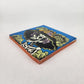 Angled view of sky blue Catrina Portrait ceramic tile showing glossy surface and natural terracotta edges