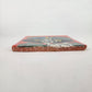 Red orange Catrina Portrait ceramic tile shown from front edge highlighting ceramic thickness and natural terracotta edge