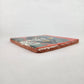 Angled view of red orange Catrina Portrait ceramic tile showing glossy surface and natural terracotta edges