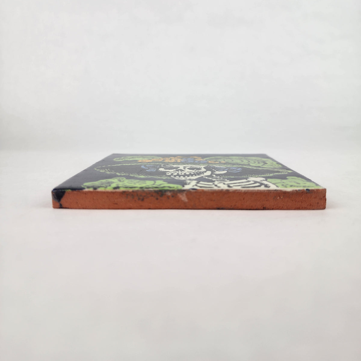 Navy blue Catrina Portrait ceramic tile shown from front edge highlighting ceramic thickness and natural terracotta edge