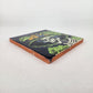 Angled view of navy blue Catrina Portrait ceramic tile showing glossy surface and natural terracotta edges