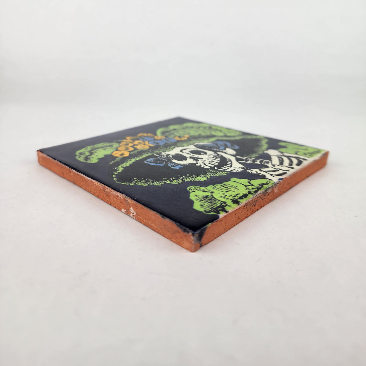 Angled view of navy blue Catrina Portrait ceramic tile showing glossy surface and natural terracotta edges