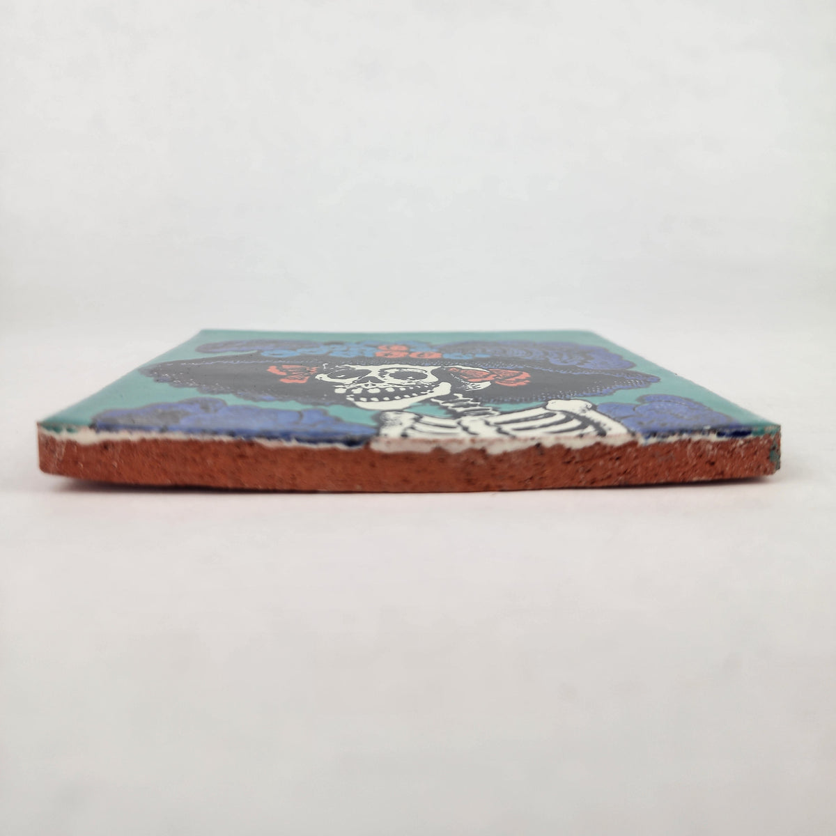 Teal Catrina Portrait ceramic tile shown from front edge highlighting ceramic thickness and natural terracotta edge
