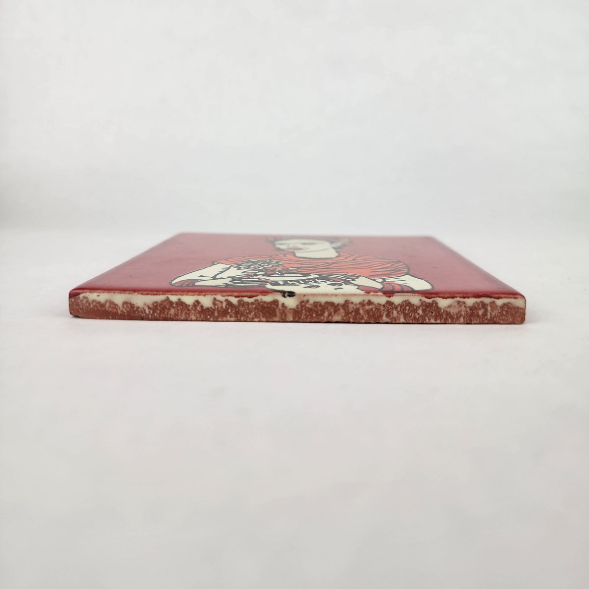 Brick red Frida Kahlo ceramic tile shown from front edge highlighting ceramic thickness and terracotta edge