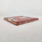 Angled view of brick red Frida Kahlo portrait ceramic tile showing glossy surface and terracotta edges