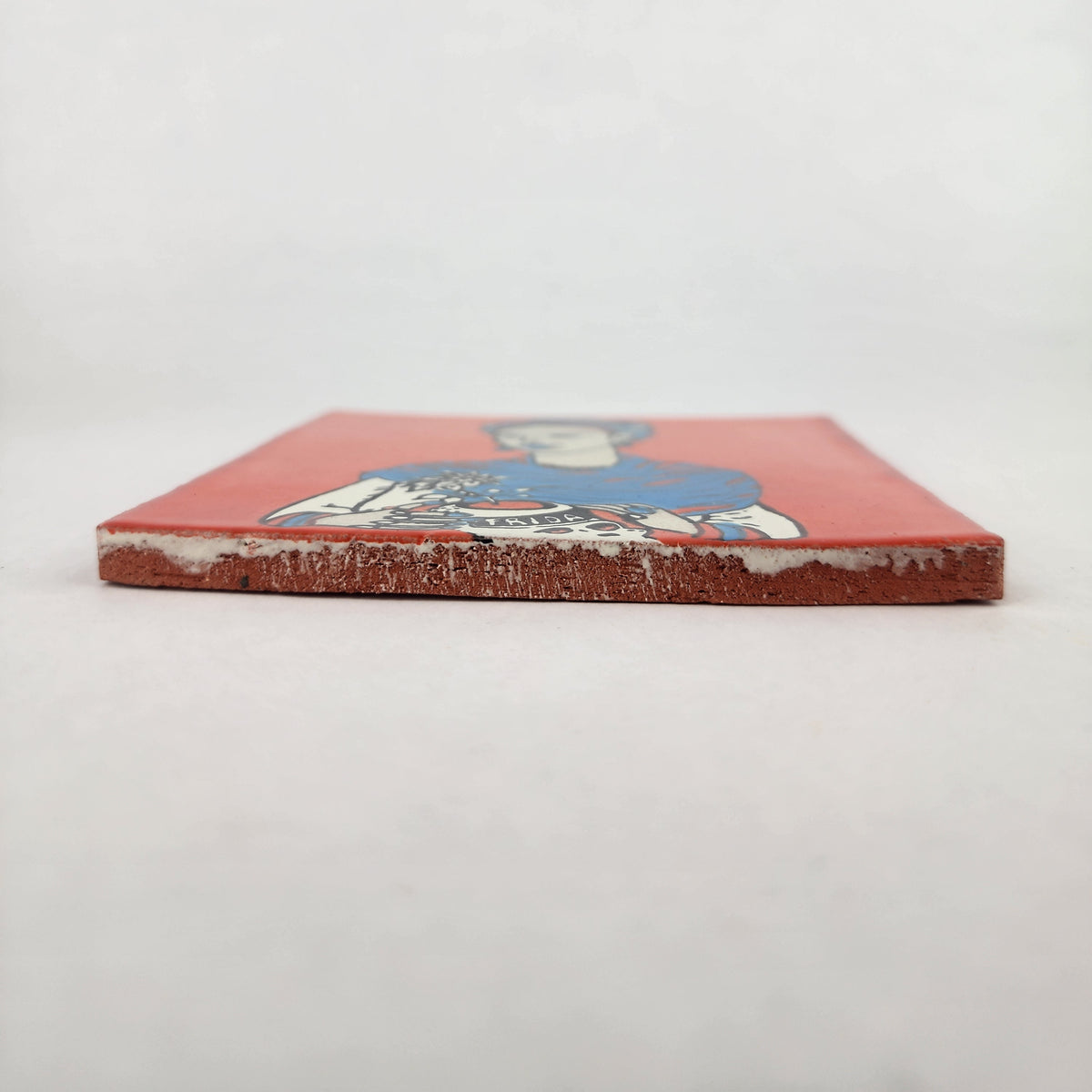 Side view of red orange Frida Kahlo portrait ceramic tile showing thickness and ceramic edge