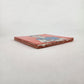 Angled view of red orange Frida Kahlo portrait ceramic tile showing glazed surface and ceramic edge