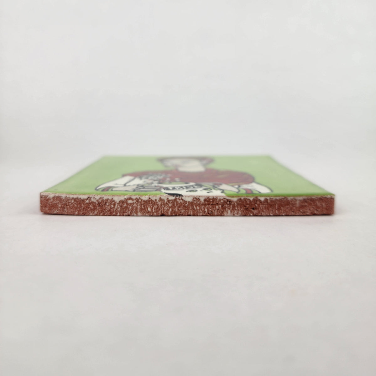 Lime green Frida Kahlo ceramic tile shown from front edge highlighting ceramic thickness and natural terracotta edge