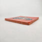 Angled view of Skeleton Motorcycle ceramic tile with red-orange background showing glazed surface and ceramic edge