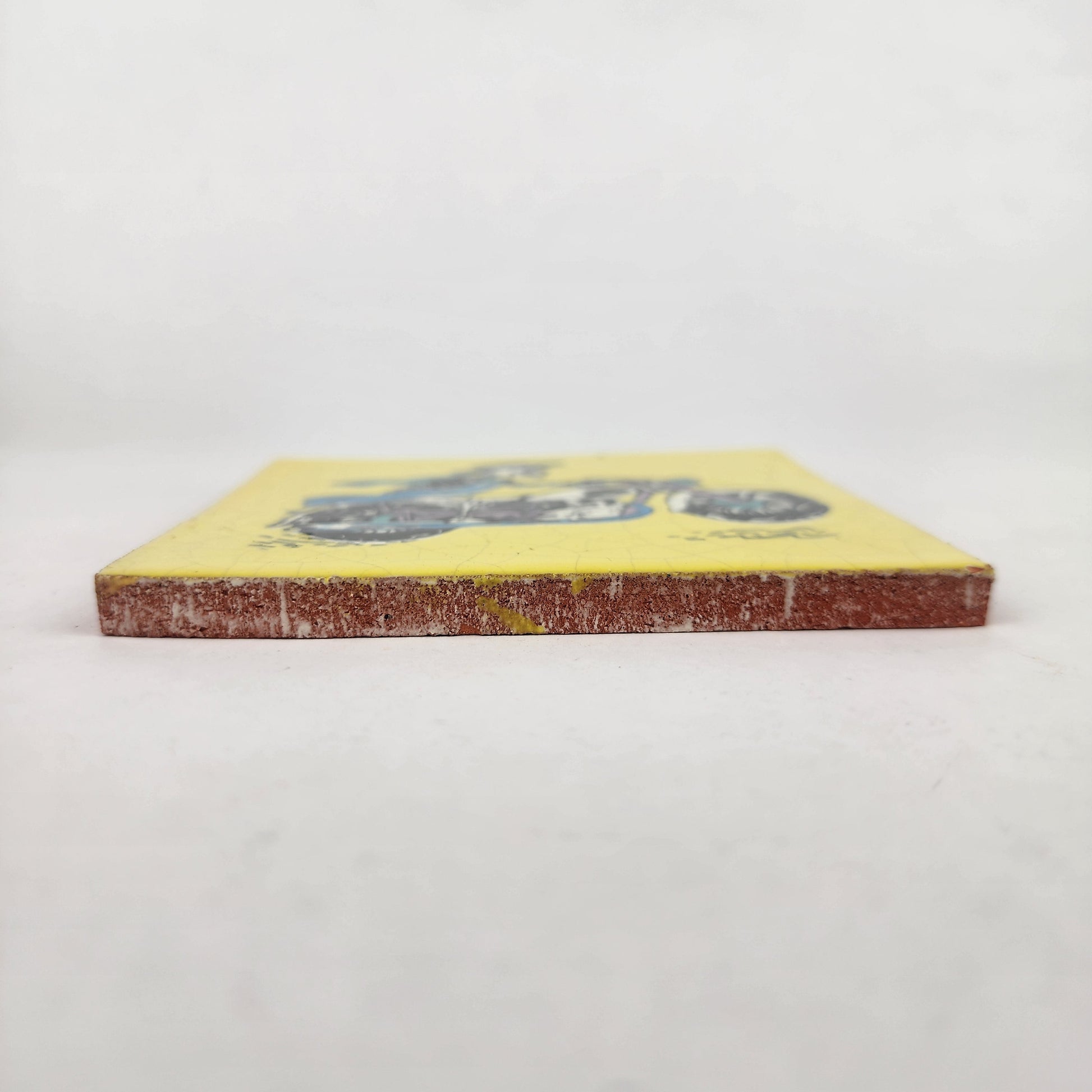 Side view of Skeleton Motorcycle ceramic tile showing thickness and unfinished ceramic edge