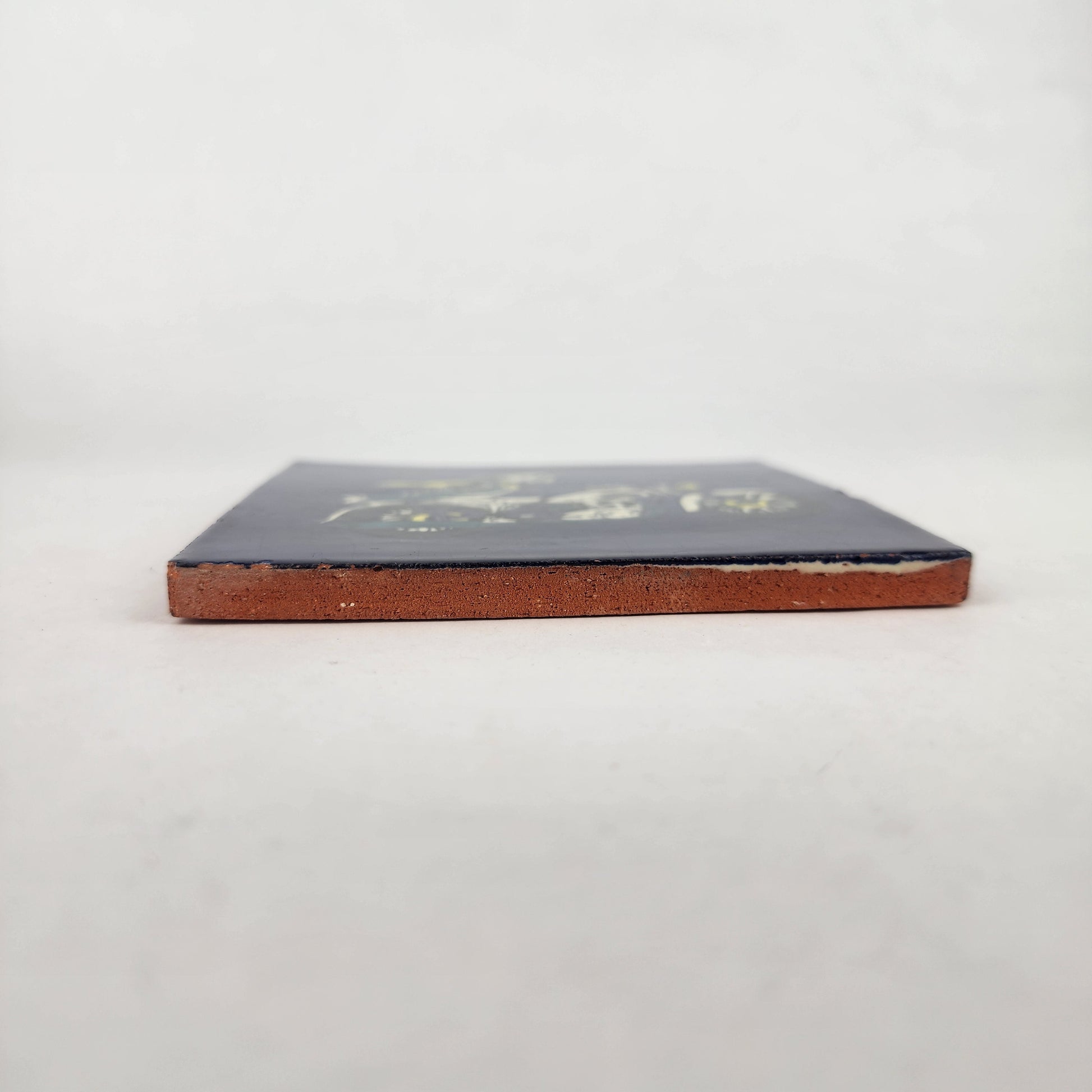 Side view of Skeleton Motorcycle ceramic tile showing thickness and unfinished ceramic edge