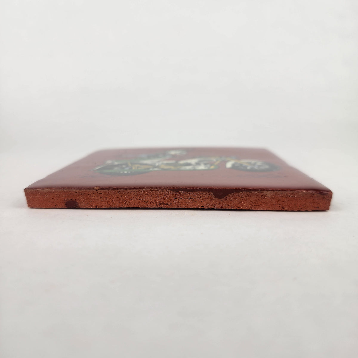 Side view of Skeleton Motorcycle ceramic tile showing thickness and unfinished ceramic edge