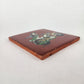 Angled view of Skeleton Motorcycle ceramic tile with red brown background showing glazed surface and ceramic edge
