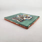 Angled view of green Mexican ceramic tile with colorful floral sugar skull design