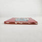 Side view of 4 1/8 inch floral sugar skull ceramic tile showing thickness and glazed edge