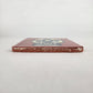 Side view of 4 1/8 inch floral sugar skull ceramic tile showing thickness and glazed edge