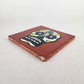 Angled view of red-brown Mexican ceramic tile with colorful floral sugar skull design