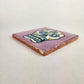 Angled view of purple Mexican ceramic tile with colorful floral sugar skull design