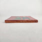 Side view of red Skeleton Couple ceramic tile showing glazed surface and terracotta edge
