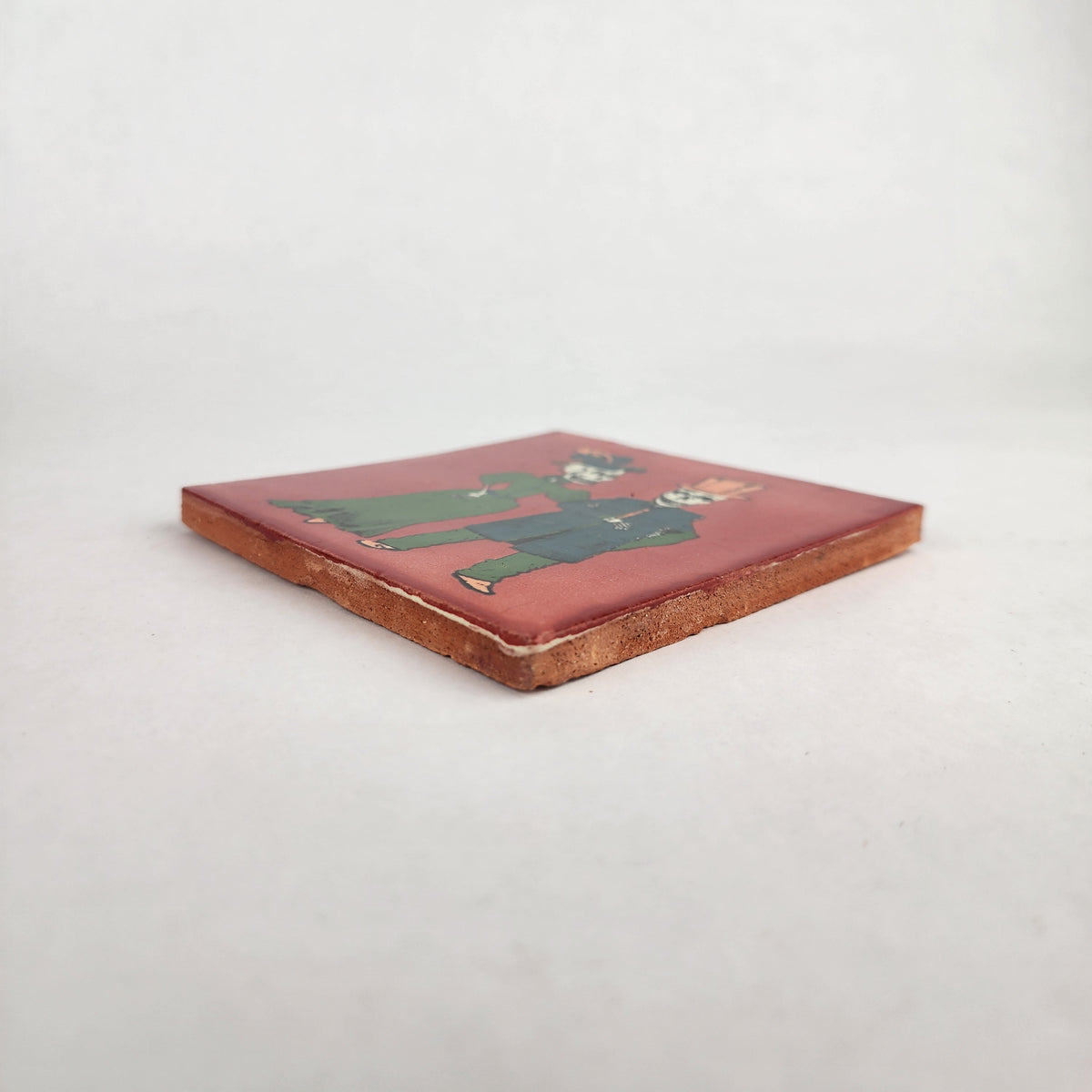 Angled view of red Skeleton Couple ceramic tile showing glossy finish and terracotta edges