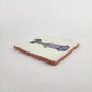 Angled view of white Catrina ceramic tile with purple dress and natural terracotta edges