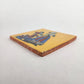 Angled view of Skeleton Serenade ceramic tile with mustard yellow background showing glazed surface and ceramic edge