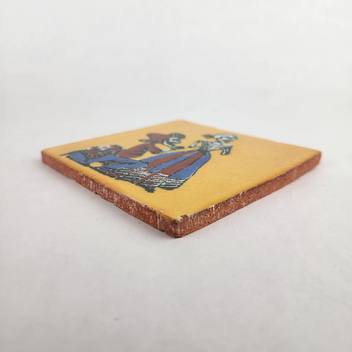 Angled view of Skeleton Serenade ceramic tile with mustard yellow background showing glazed surface and ceramic edge