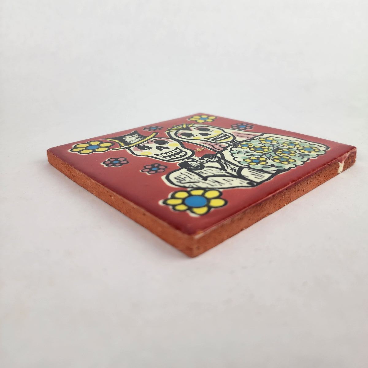 Angled view of red skeleton wedding ceramic tile showing glazed surface and ceramic edge