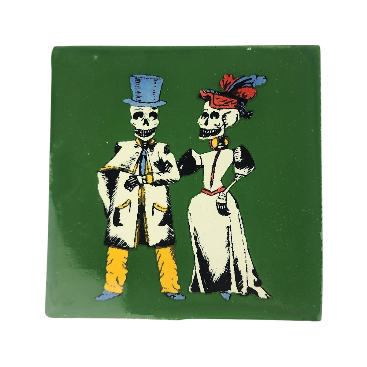 A square green ceramic tile featuring a vintage-style illustration of two skeleton figures dressed in formal attire, one in a blue top hat and coat with yellow trousers, and the other in a white dress with a red and blue feathered hat.