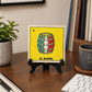 Black wood display stand holding El Barril Lotería ceramic tile on a home office desk