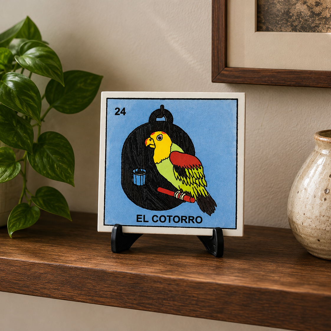 Black acrylic display stand holding El Cotorro Lotería ceramic tile on a home shelf